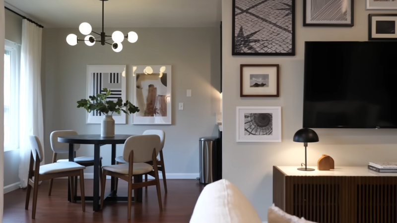 A Modern Dining Area with Neutral Wall Colors, Contemporary Art Pieces, a Minimalist Black Table, and Light Wooden Chairs, Enhanced by Bright Natural Light